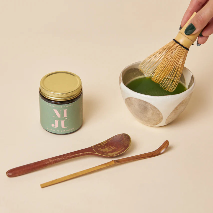 Jar of ceremonial matcha with chasen and a bowl of matcha