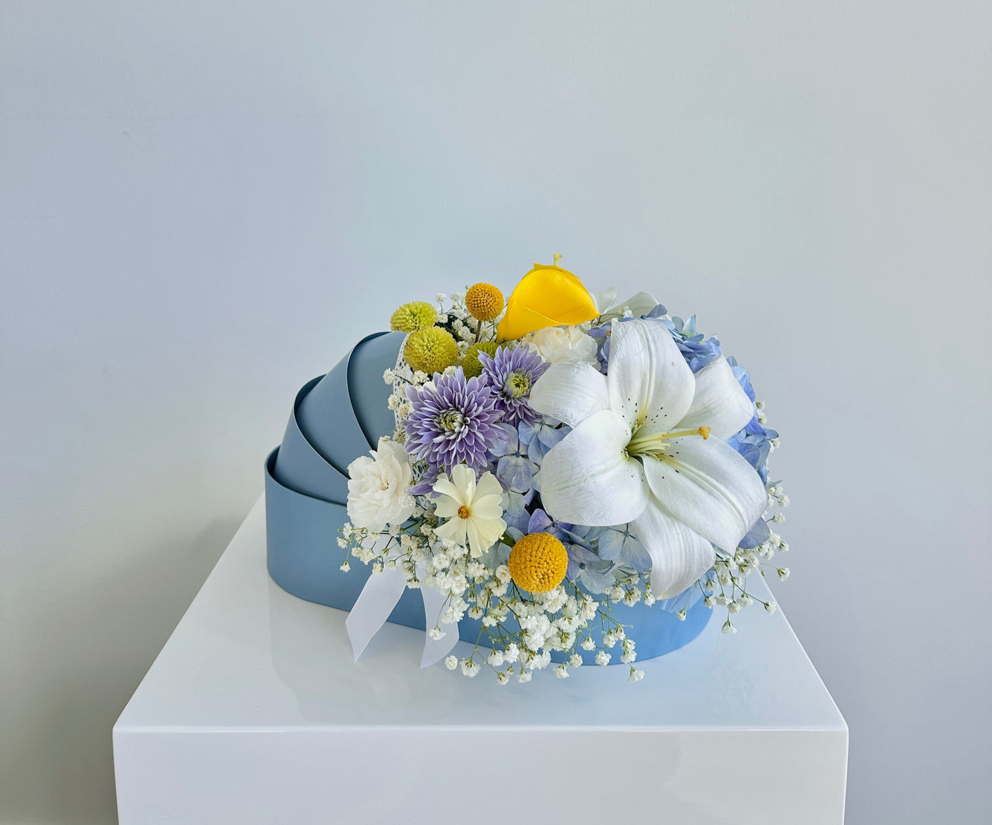 Blue, white, yellow fresh flowers in a blue baby cradle made of recyclable thick paper