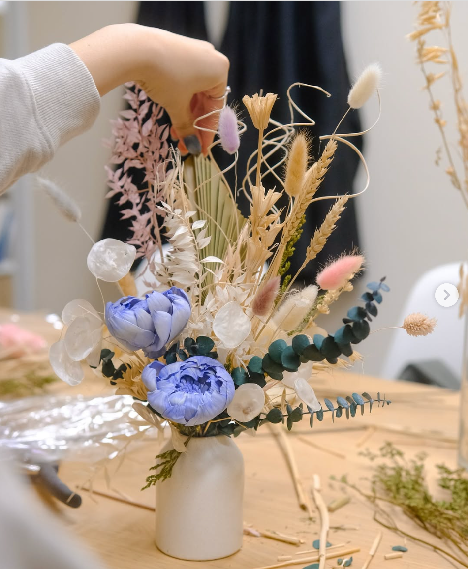 Bouquet of dried flowers in a white vase on a wooden surface