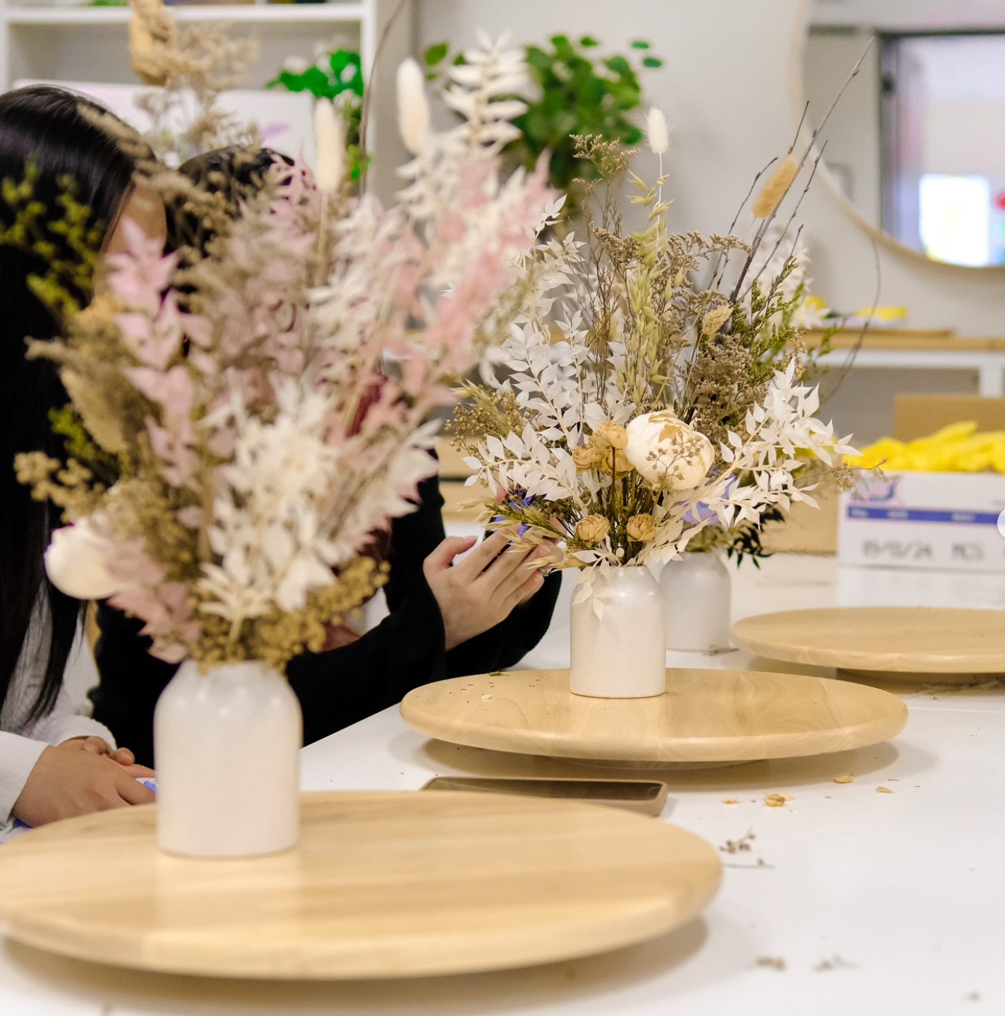 dried flower arrangements in white ceramic vases during a workshop