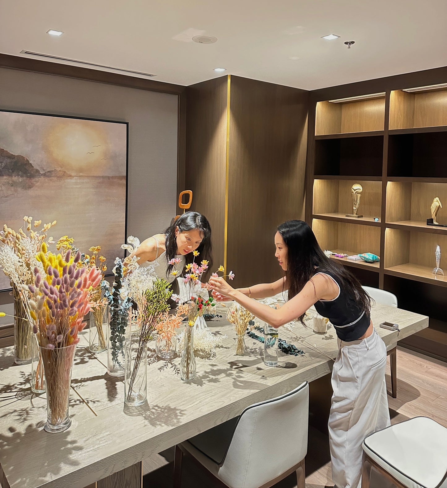 Two women arranging flowers in a modern room