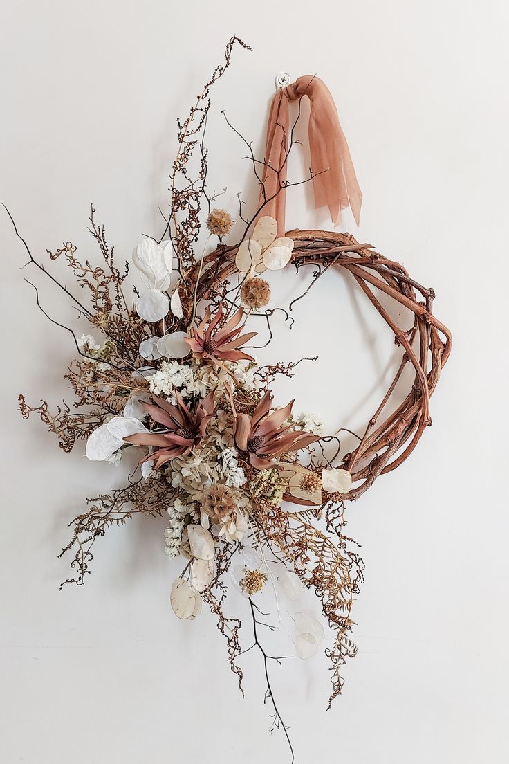 Decorative wreath with dried flowers and a pink ribbon on a white background