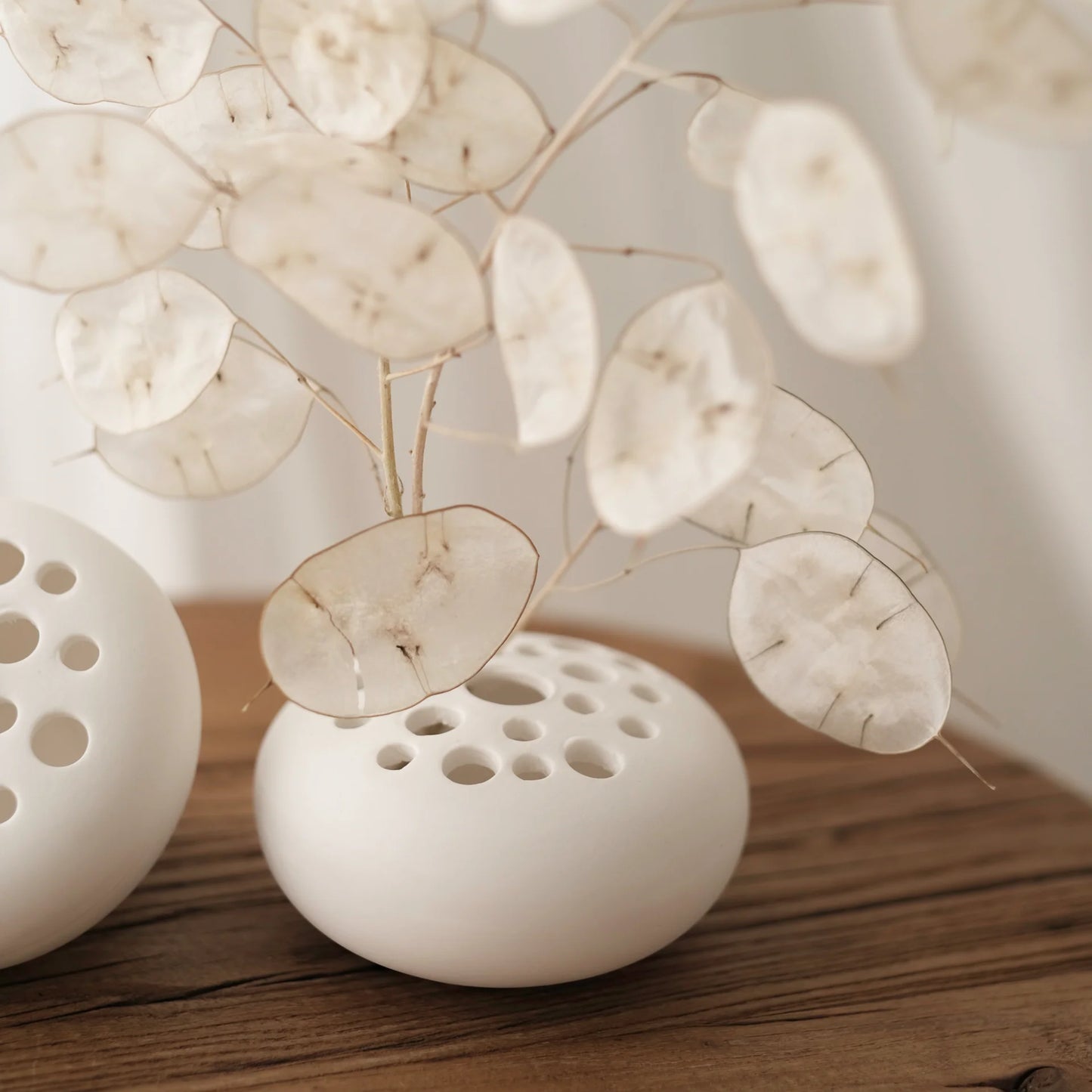 White ceramic flower frog with dried flowers on a wooden surface