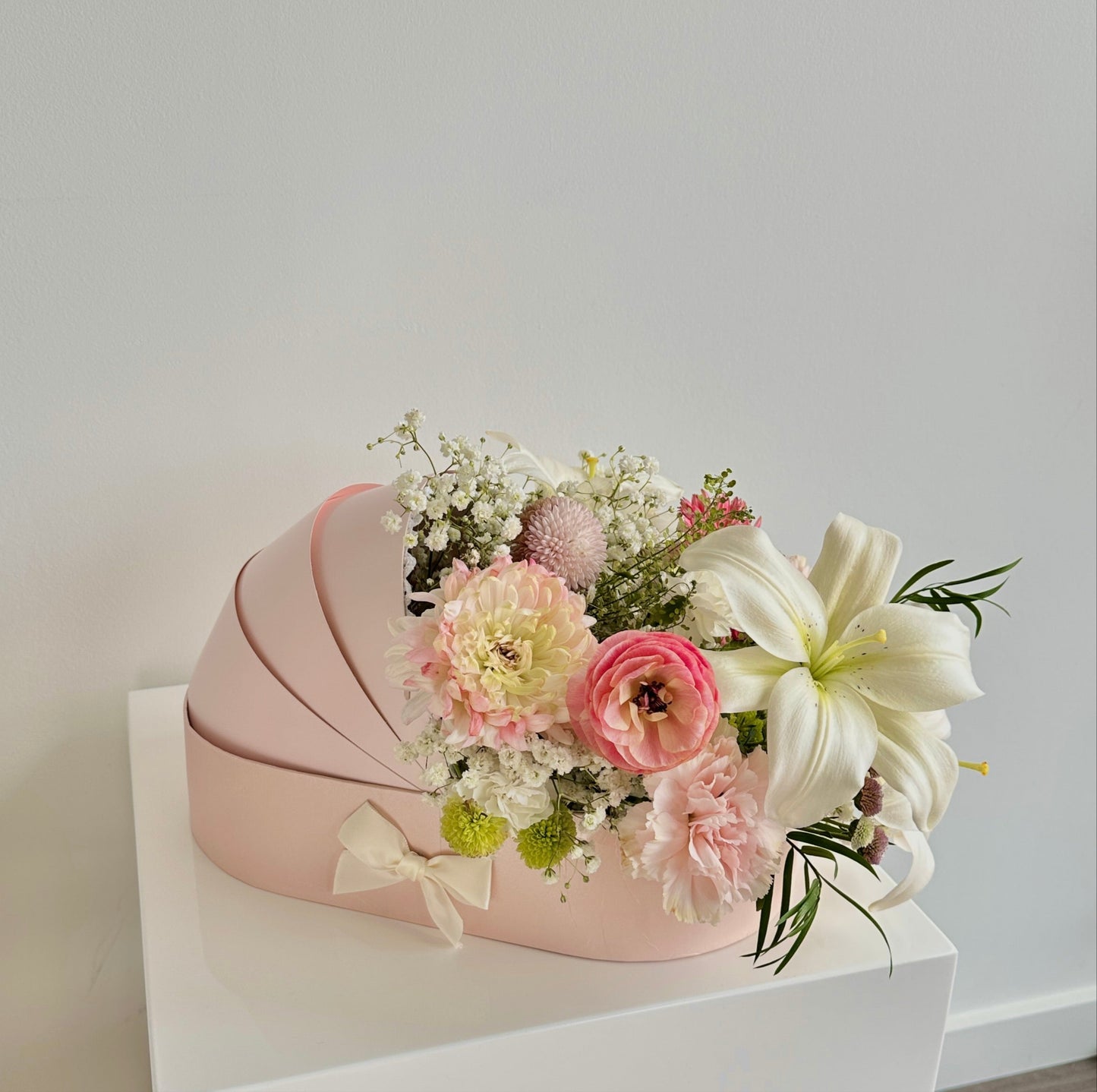 Fresh flowers in a pink baby cradle made of recyclable thick paper