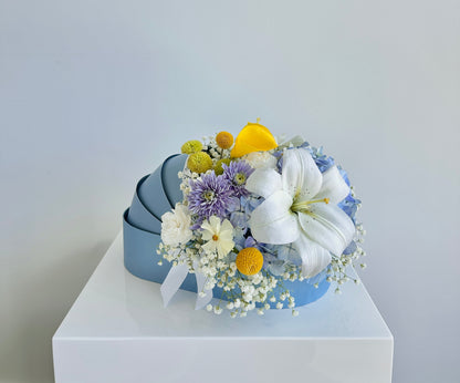 Blue, white, yellow fresh flowers in a blue baby cradle made of recyclable thick paper