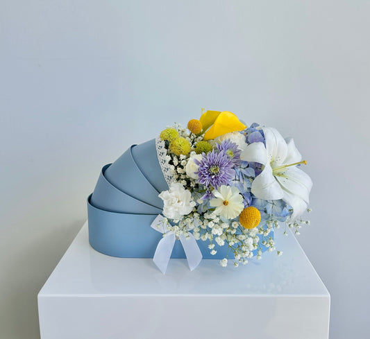 Fresh flowers in a blue baby cradle made of recyclable thick paper
