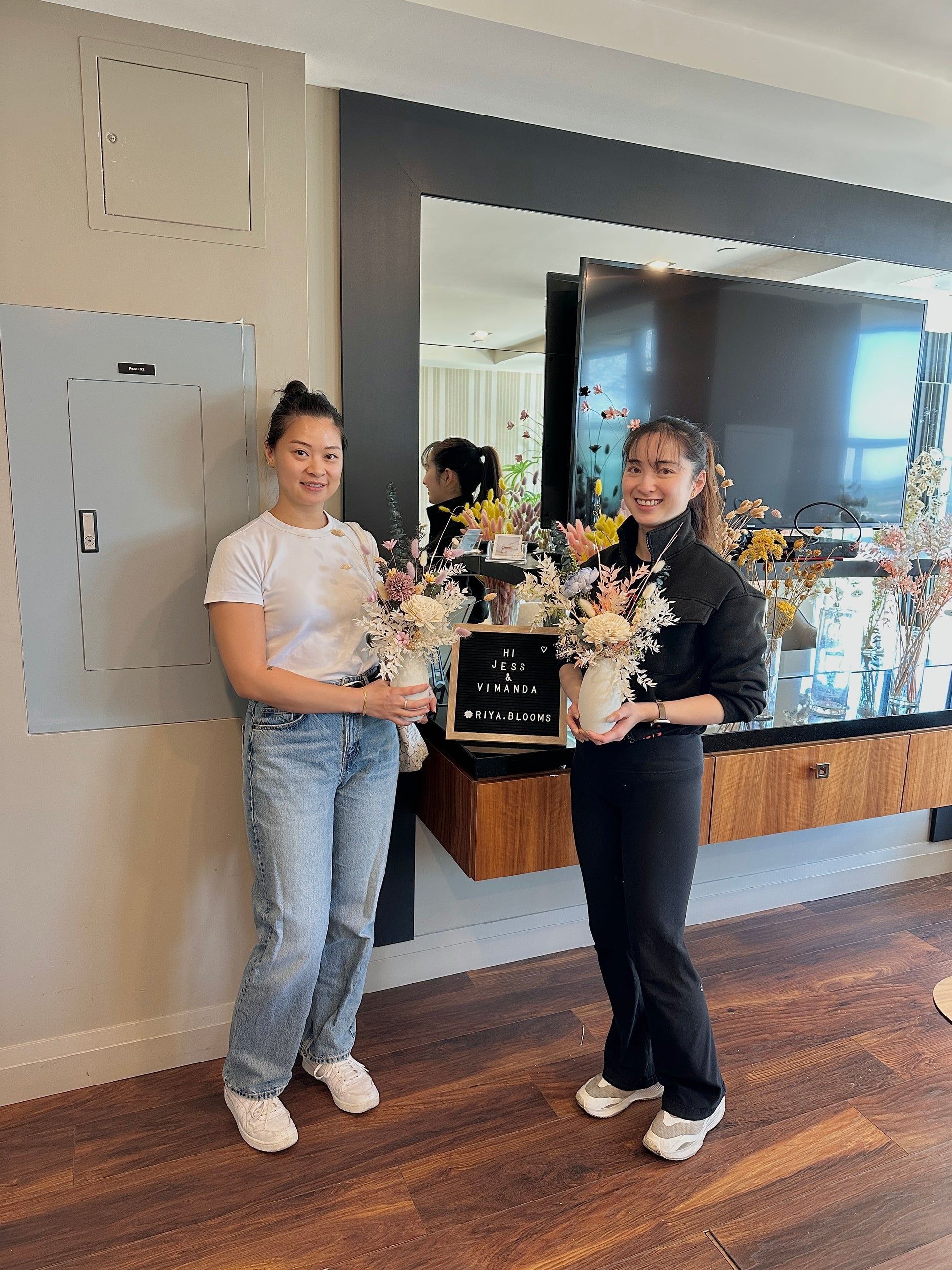 Two people holding bouquets of flowers in a modern room