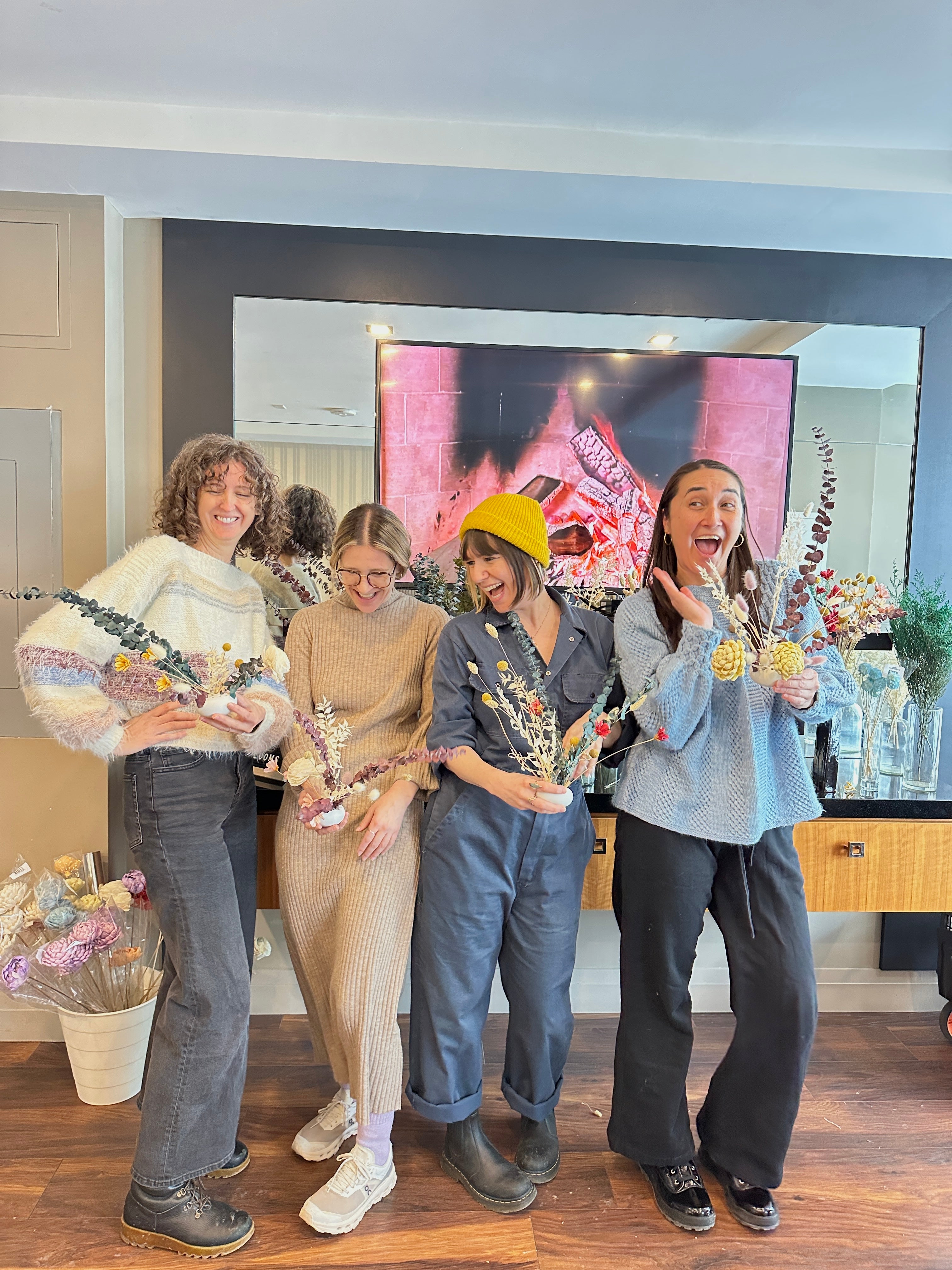 Four women standing together in a room holding decorative items.