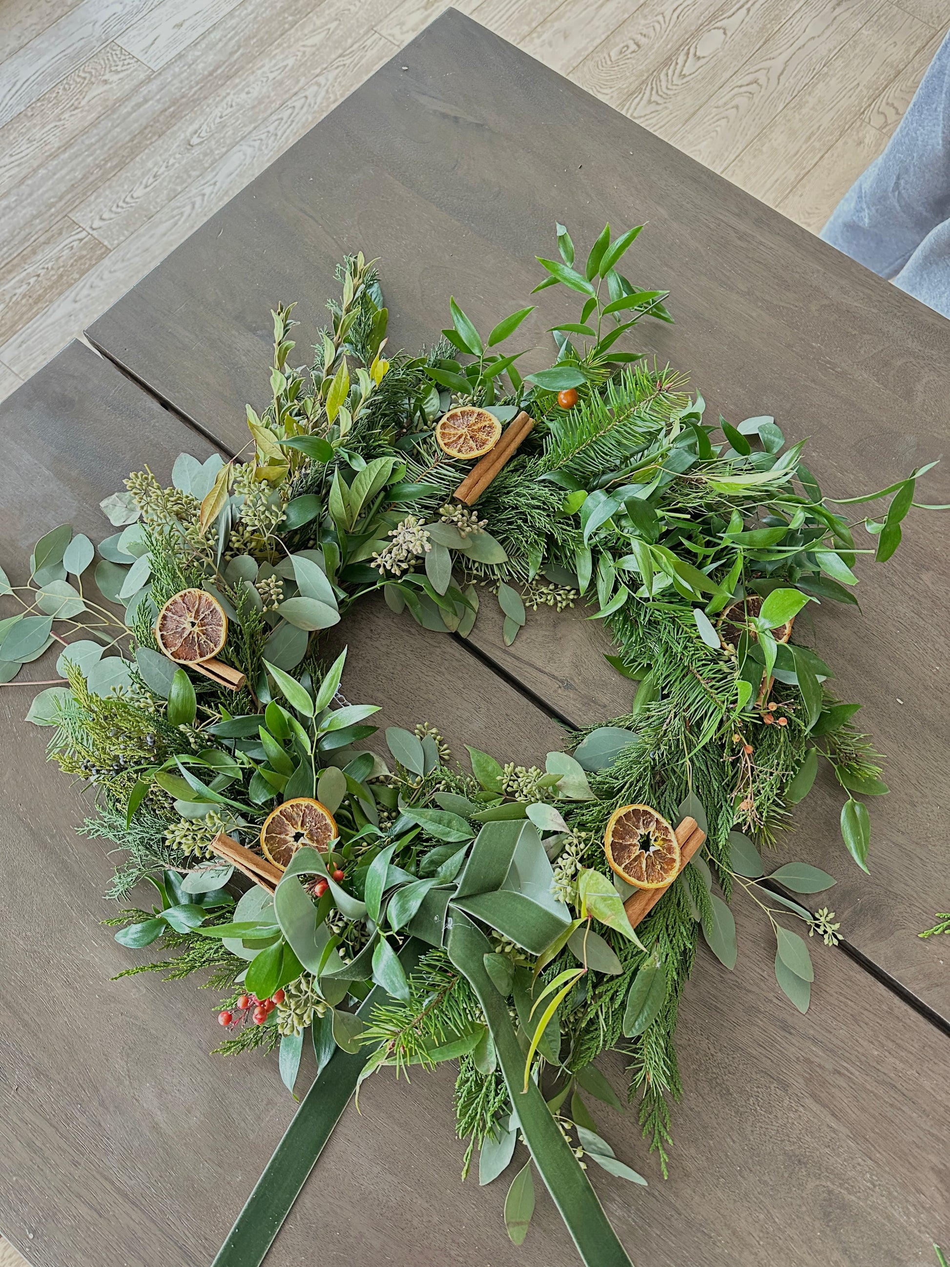 Green wreath with dried oranges on a wooden surface