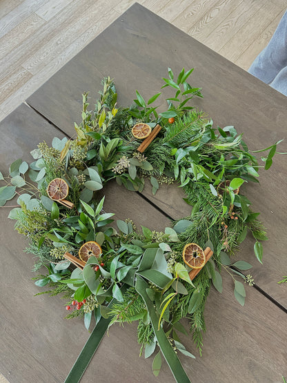 Green wreath with dried oranges on a wooden surface