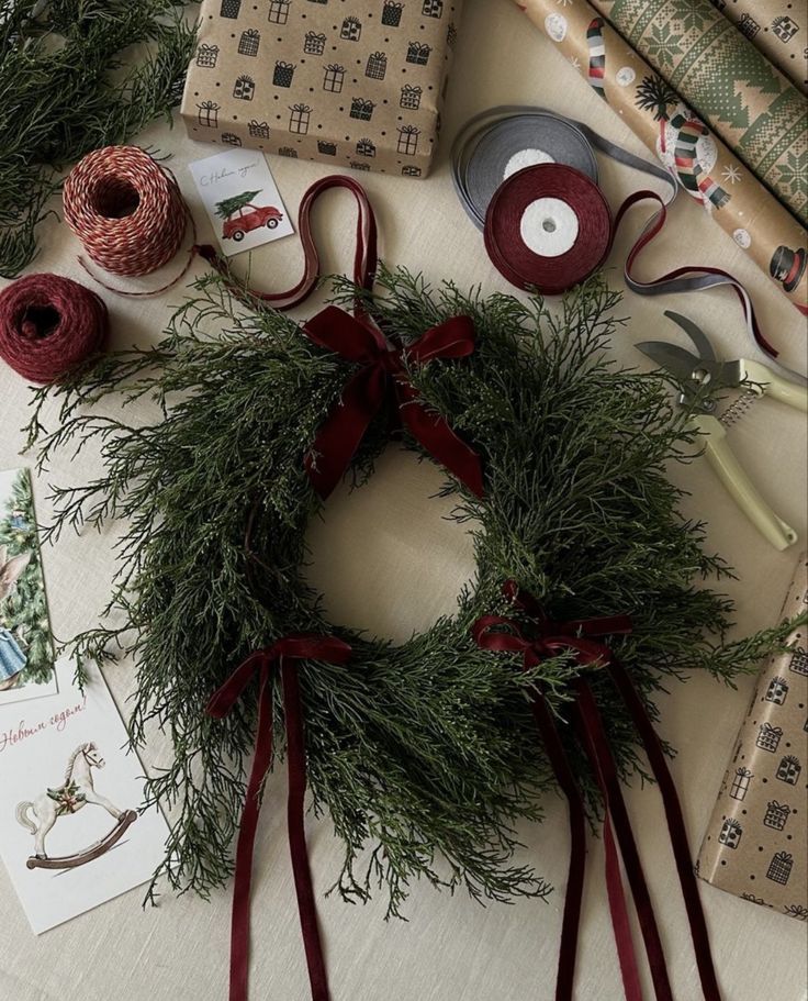 Christmas wreath with red ribbons on a table with gift wrap and scissors