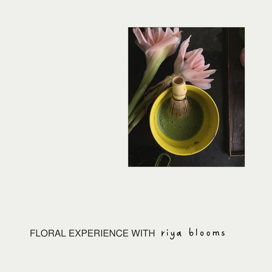 Yellow teacup with a whisk and pink flowers on a dark surface, labeled 'Floral Experience with riya blooms'.