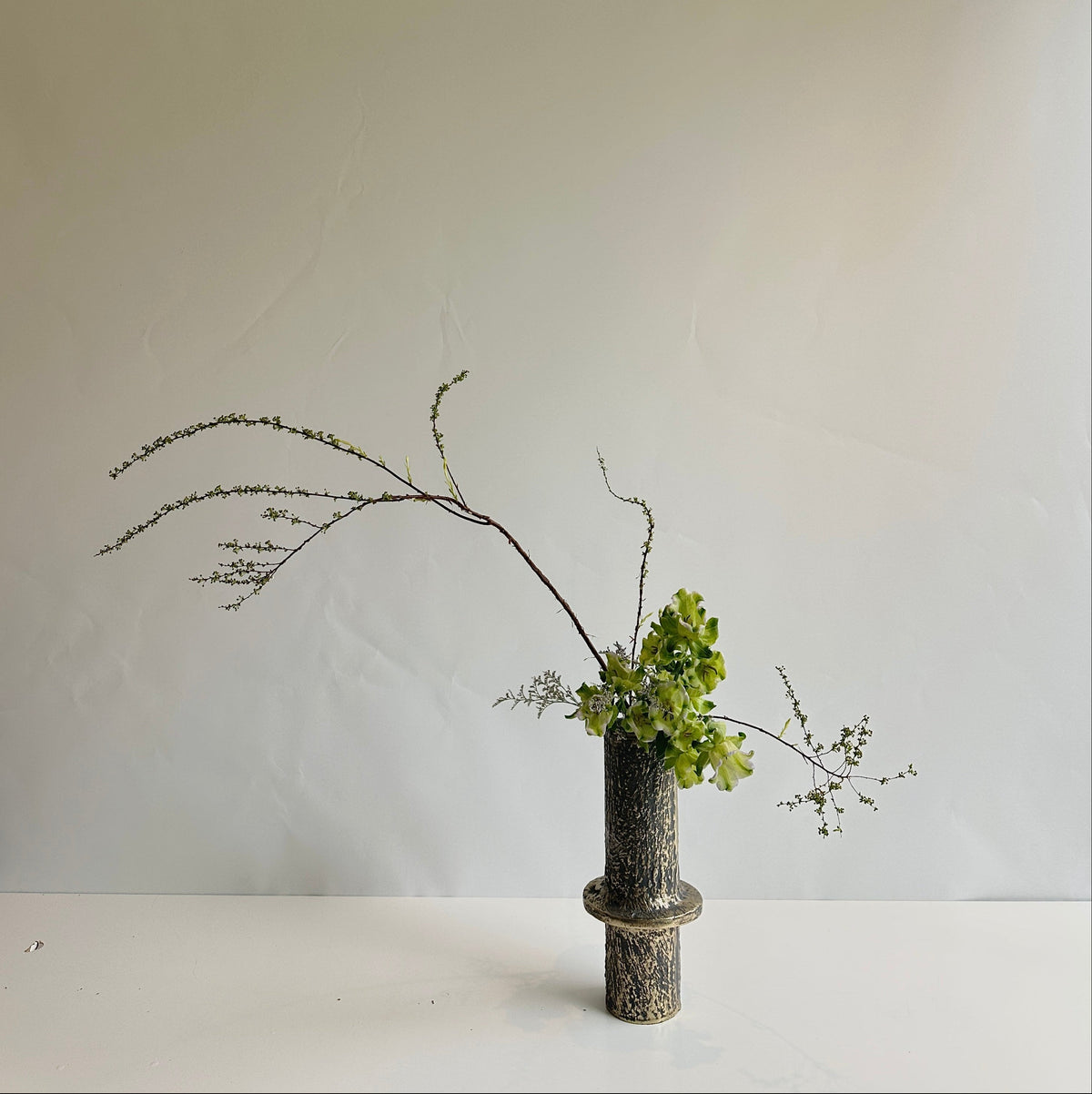 Ikebana vase arrangement on a white surface and background
