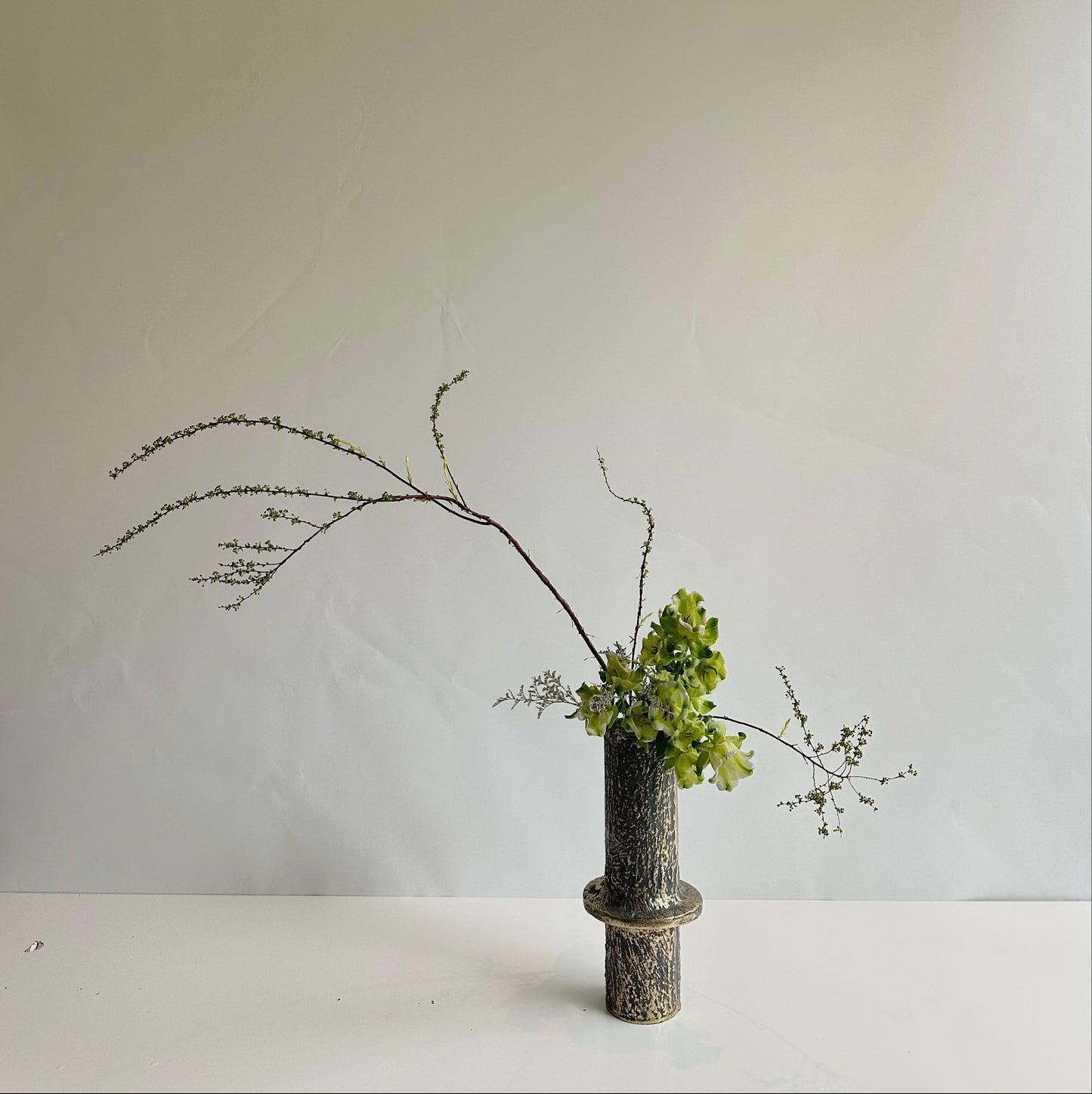 Ikebana vase arrangement on a white surface and background
