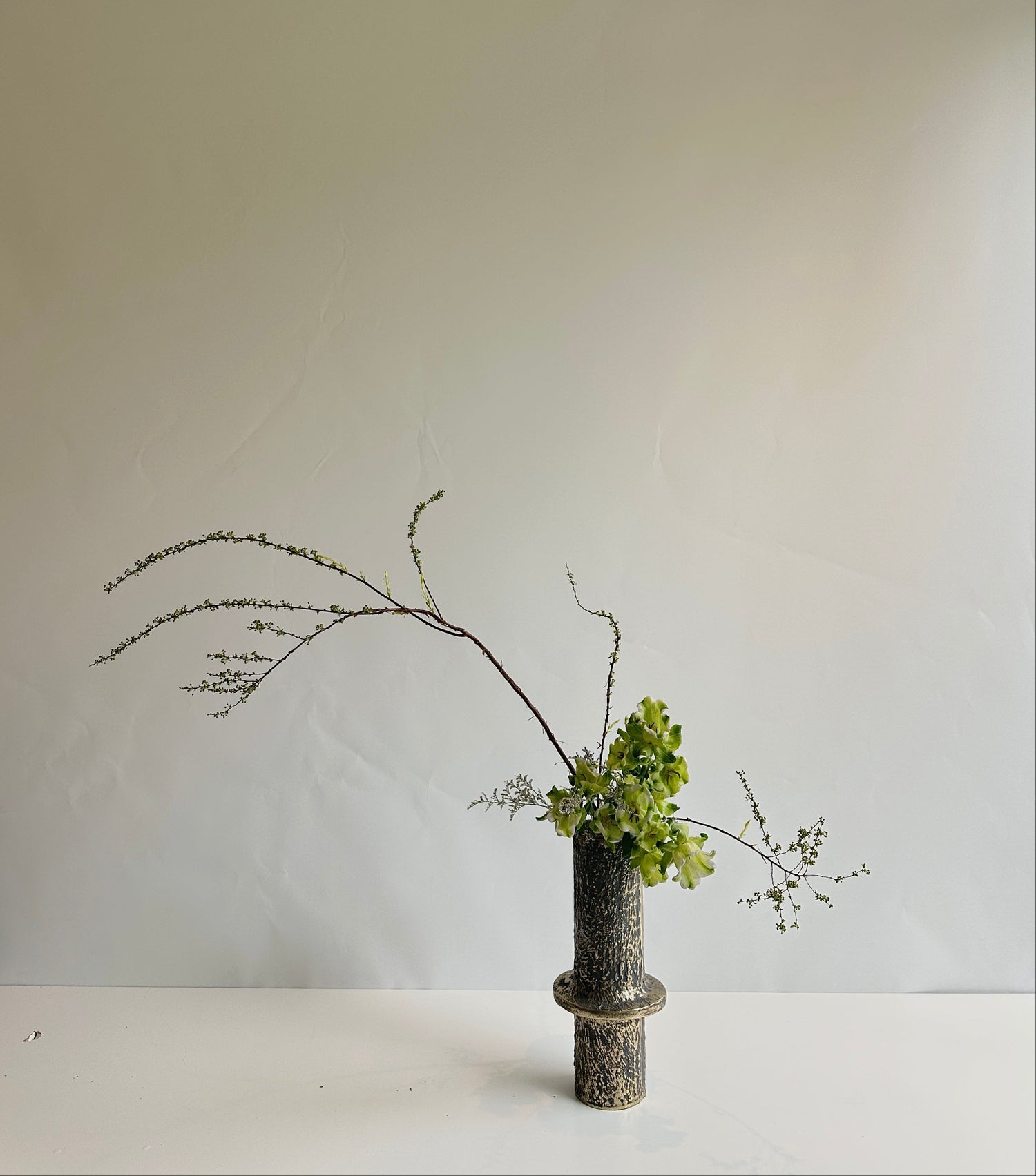 Ikebana vase arrangement on a white surface and background