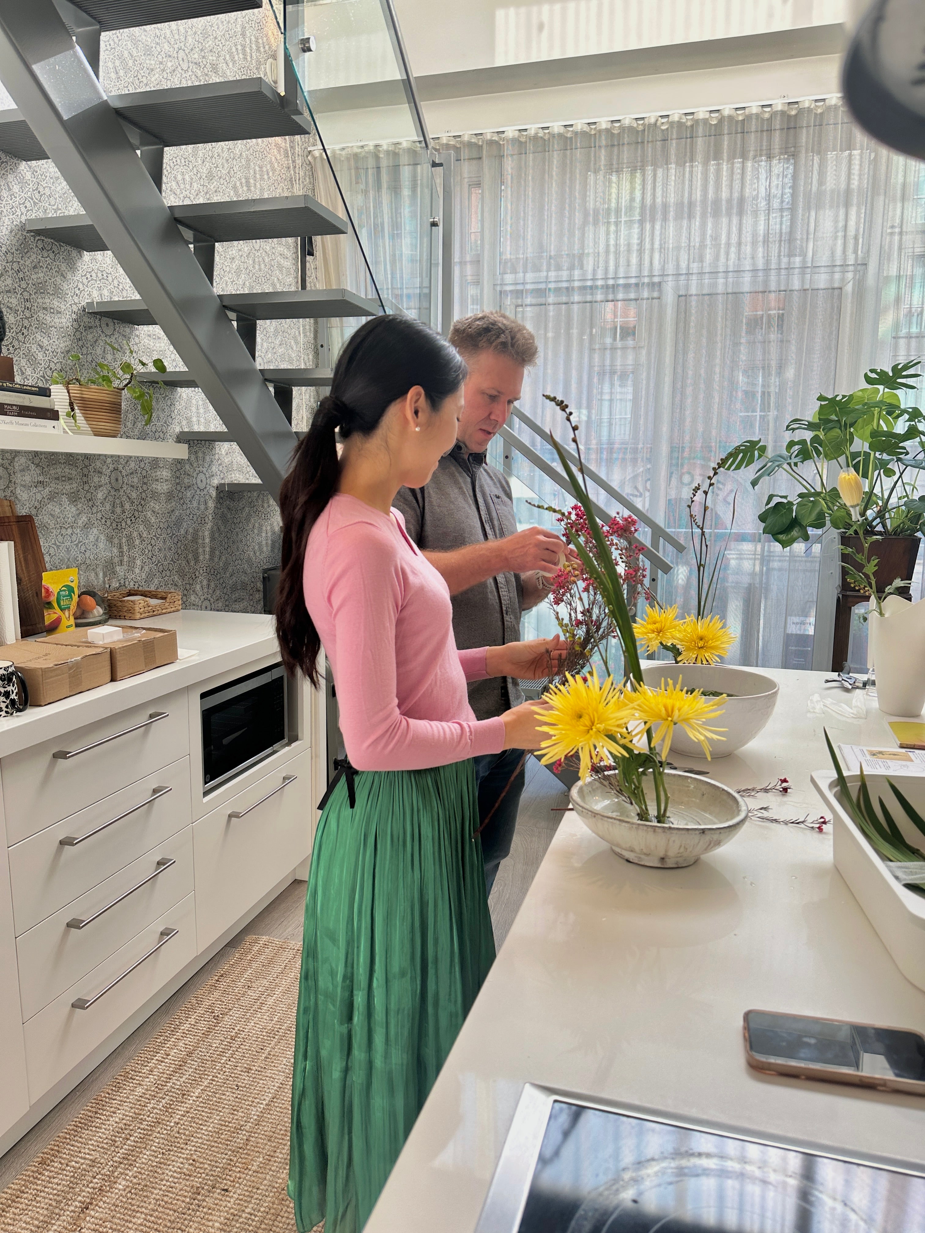 Two people arranging flowers in a modern kitchen.