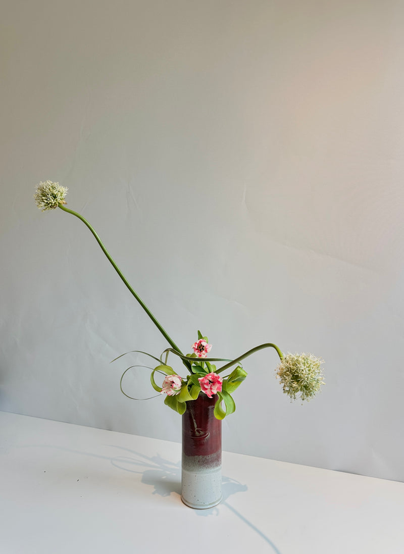Vase with flowers on a white surface against a plain background
