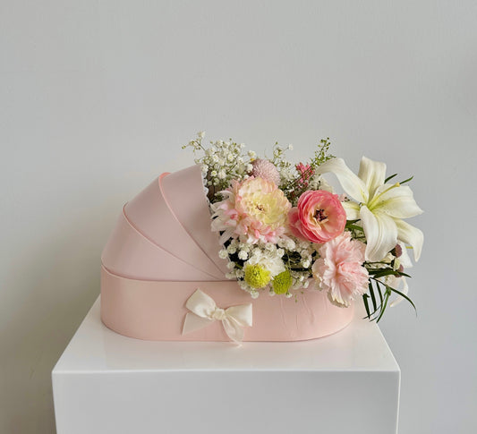 Fresh flowers in a pink baby cradle made of recyclable thick paper