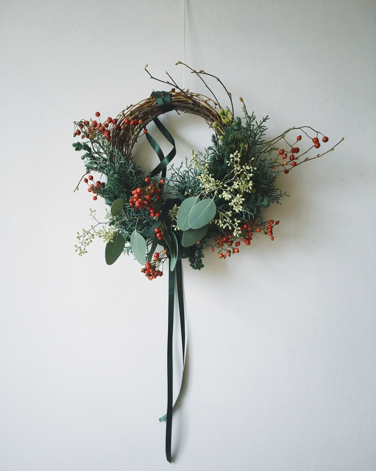 Decorative wreath with greenery and berries on a white background