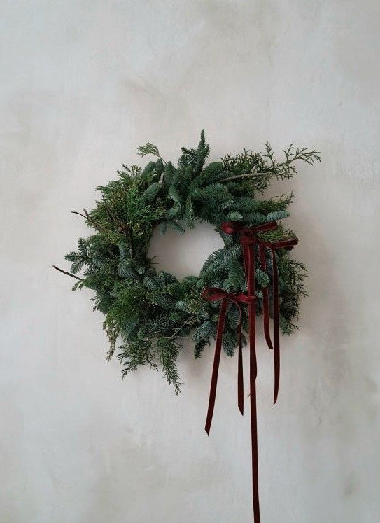 Green wreath with red ribbons on a white wall