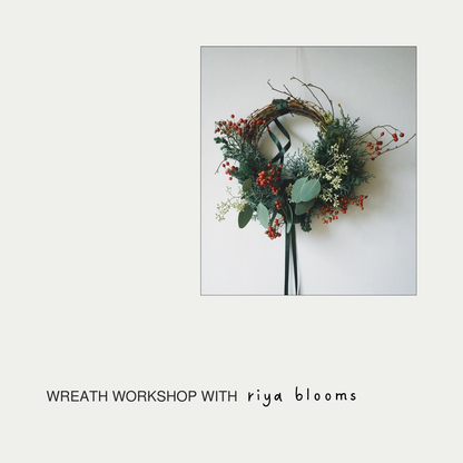 Decorative wreath with greenery and berries on a white background, featuring 'riya blooms' text.